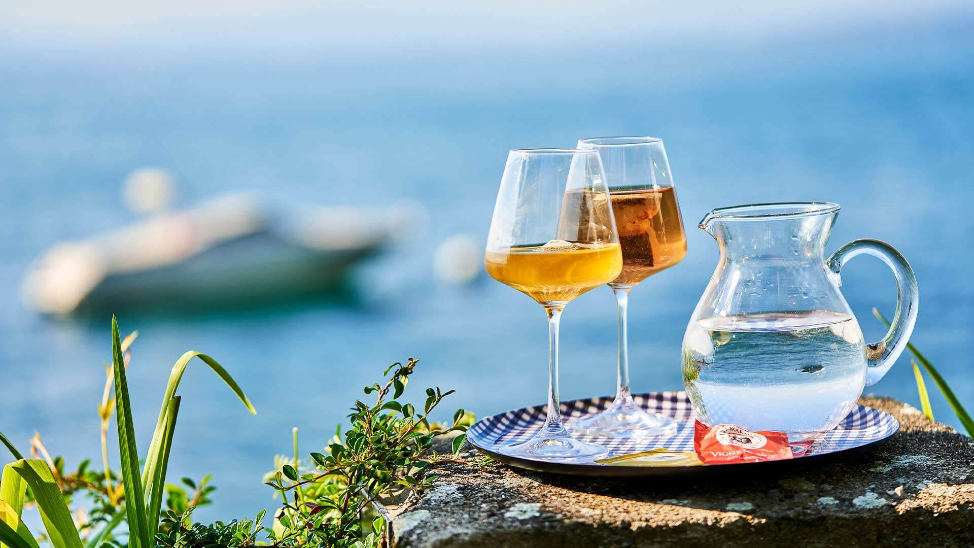 2 verres à pied avec infusions froides sur un rebord avec vue sur lac Léman